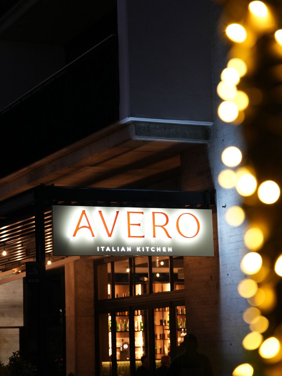 The illuminated Avero Italian Kitchen sign above the entrance at dusk